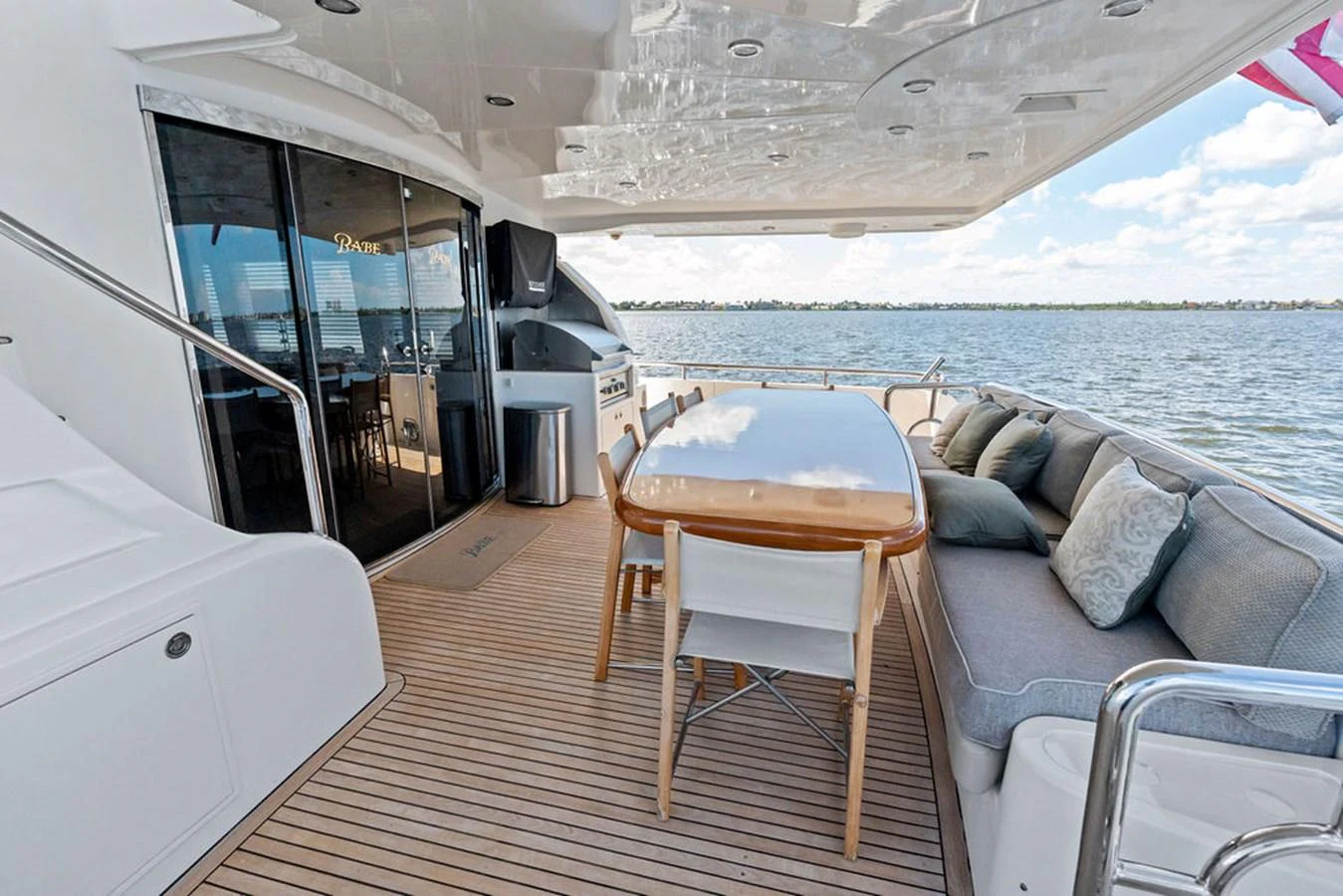 The aft deck features a spacious dining area with a comfortable sofa and a large table, perfect for alfresco dining. aboard BABE Yacht for Sale