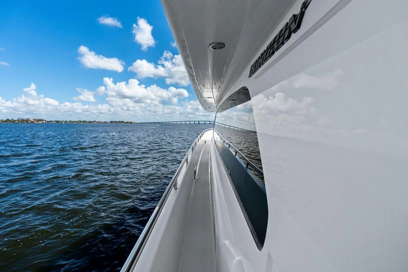 A sleek yacht cruises smoothly on calm waters under a bright blue sky. aboard BABE Yacht for Sale