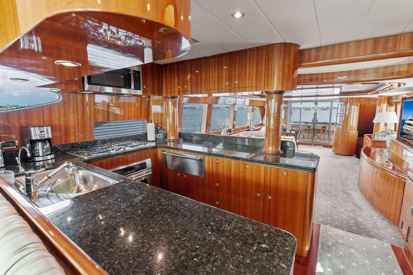 The yacht's galley features sleek wooden cabinetry, modern appliances, and a spacious countertop with a view of the water. aboard BABE Yacht for Sale