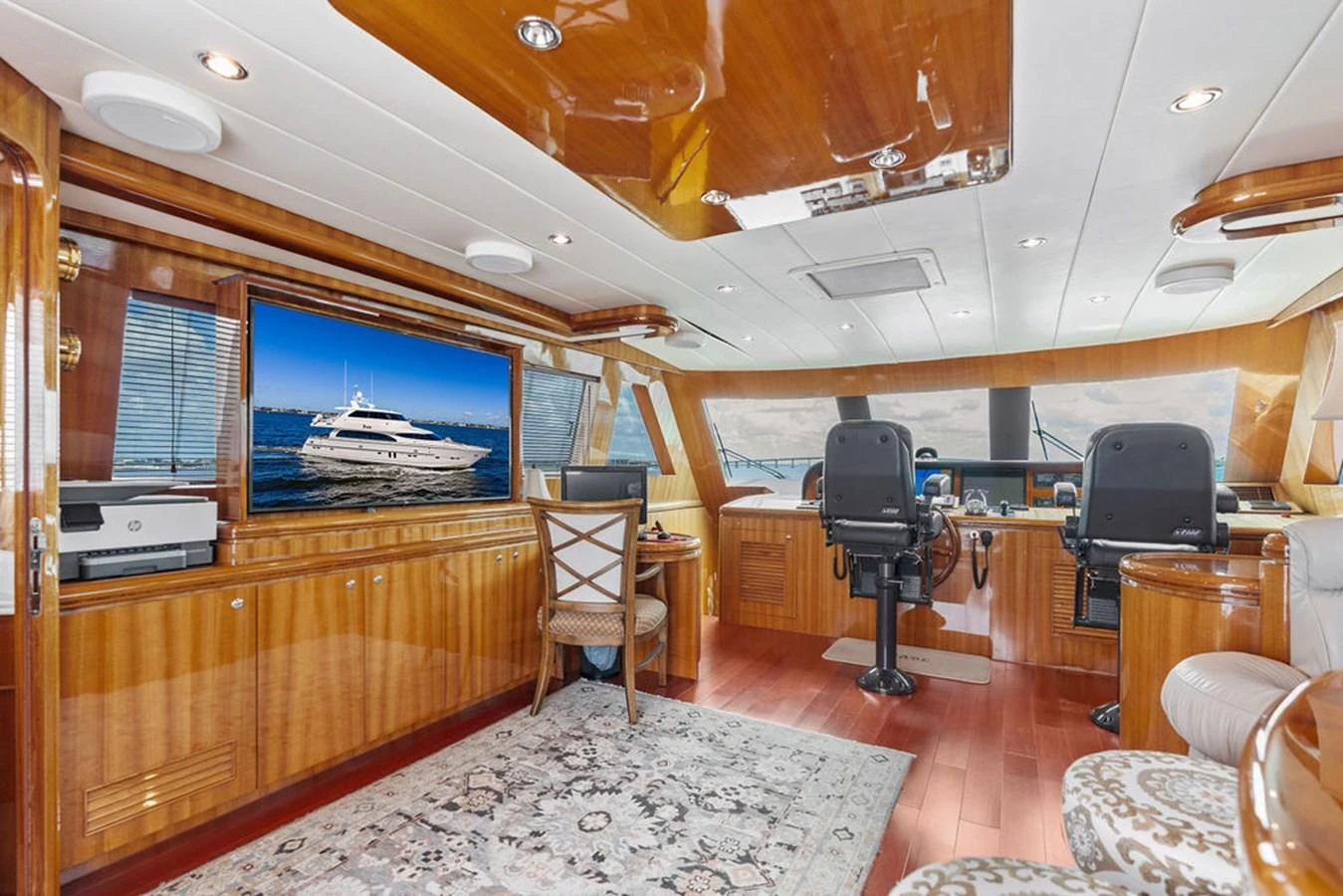 The helm area features luxurious wood finishes, a large screen, and comfortable seating. aboard BABE Yacht for Sale