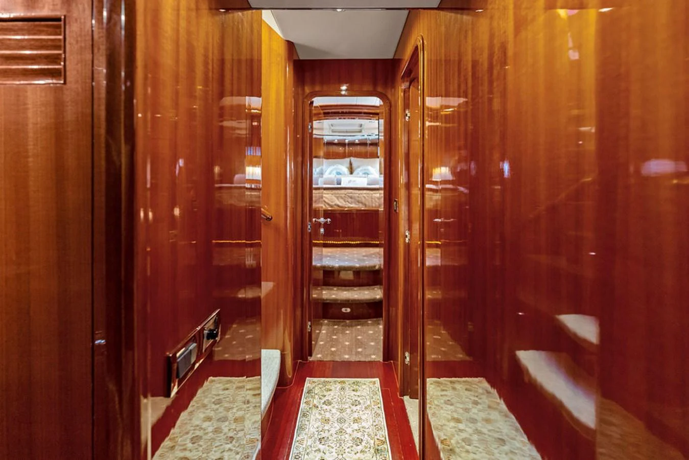 The yacht's interior features a polished wooden hallway leading to a cozy stateroom. aboard BABE Yacht for Sale
