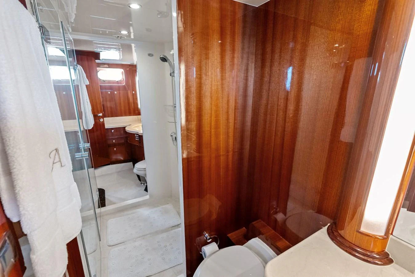 The yacht's bathroom features rich wood paneling and a glass-enclosed shower. aboard BABE Yacht for Sale