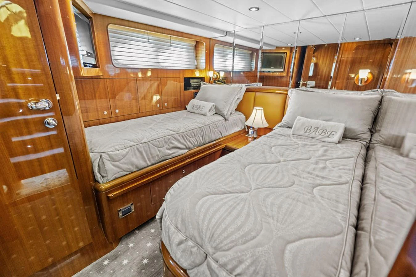 The guest stateroom features twin beds with luxurious bedding and warm wooden finishes. aboard BABE Yacht for Sale