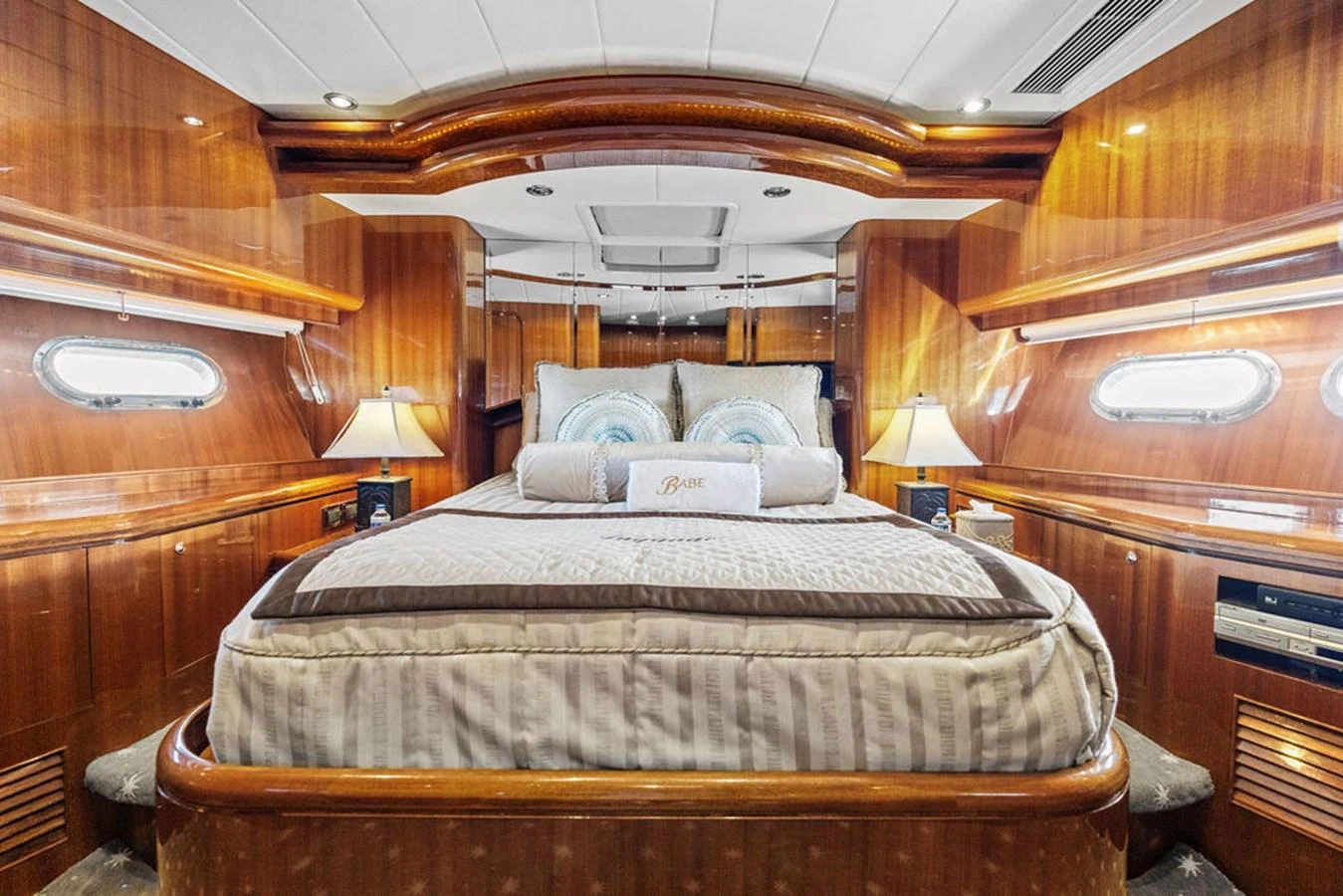 The master stateroom features a luxurious bed with elegant wood paneling and ambient lighting. aboard BABE Yacht for Sale