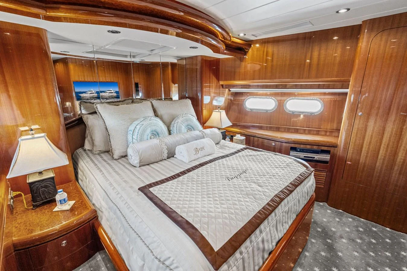 The stateroom features luxurious bedding and elegant wood paneling, creating a warm and inviting atmosphere. aboard BABE Yacht for Sale