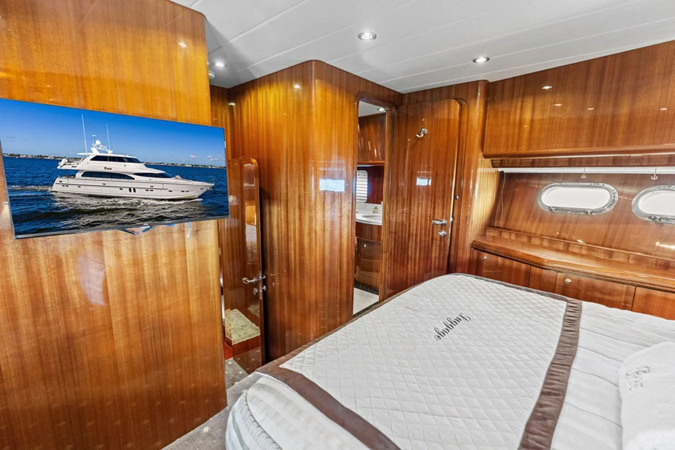 A luxurious stateroom featuring a comfortable bed, rich wood paneling, and a flat-screen TV. aboard BABE Yacht for Sale