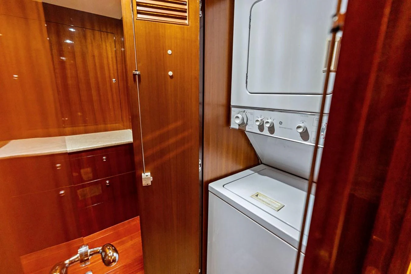 The yacht features a compact and efficient laundry area with a stacked washer and dryer. aboard BABE Yacht for Sale