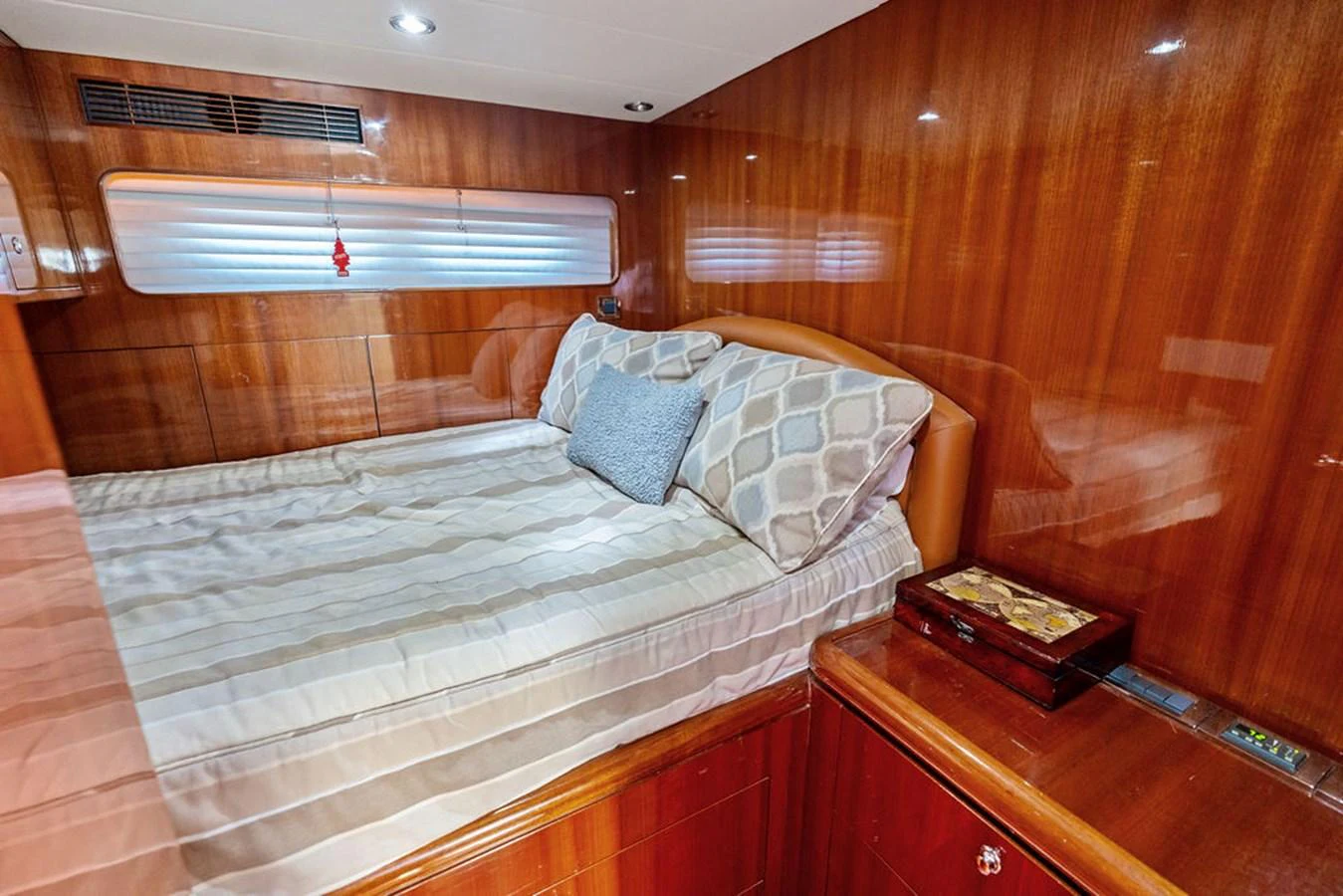 The stateroom features a cozy bed with elegant wood paneling and soft lighting. aboard BABE Yacht for Sale