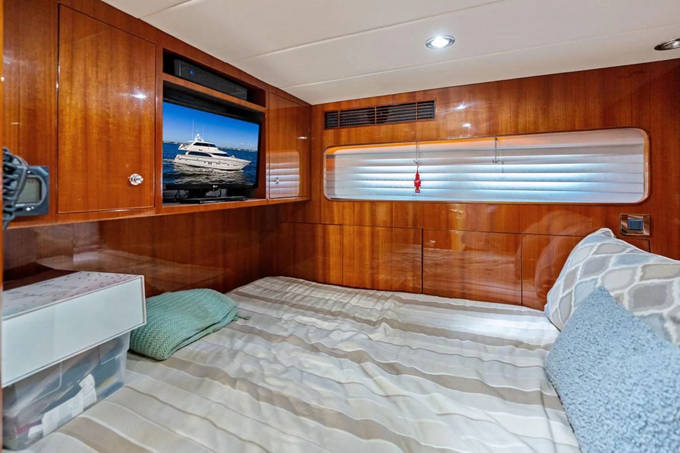 A cozy cabin with a comfortable bed and a television displaying a yacht image. aboard BABE Yacht for Sale