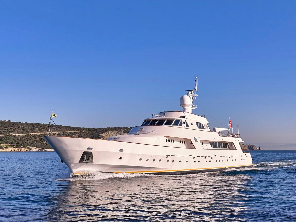 A sleek and elegant yacht cruises smoothly on calm waters under a clear blue sky. aboard RESINA Yacht for Sale