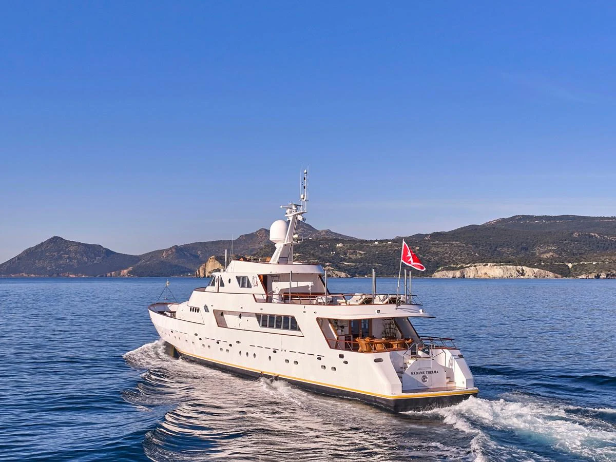 A luxurious yacht cruises through calm waters with scenic mountains in the background. aboard RESINA Yacht for Sale