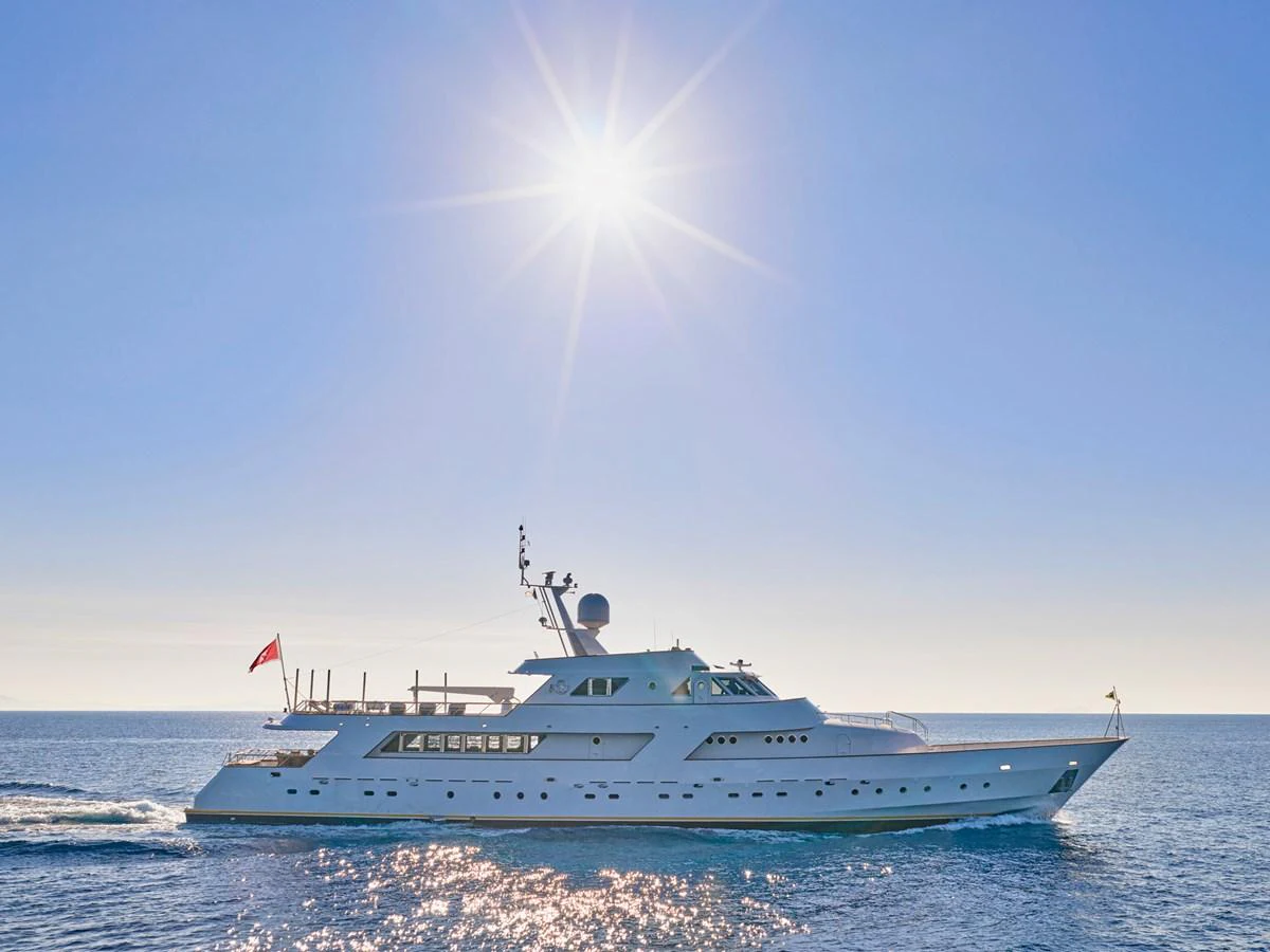 A sleek yacht cruises under a bright sun on calm waters. aboard RESINA Yacht for Sale