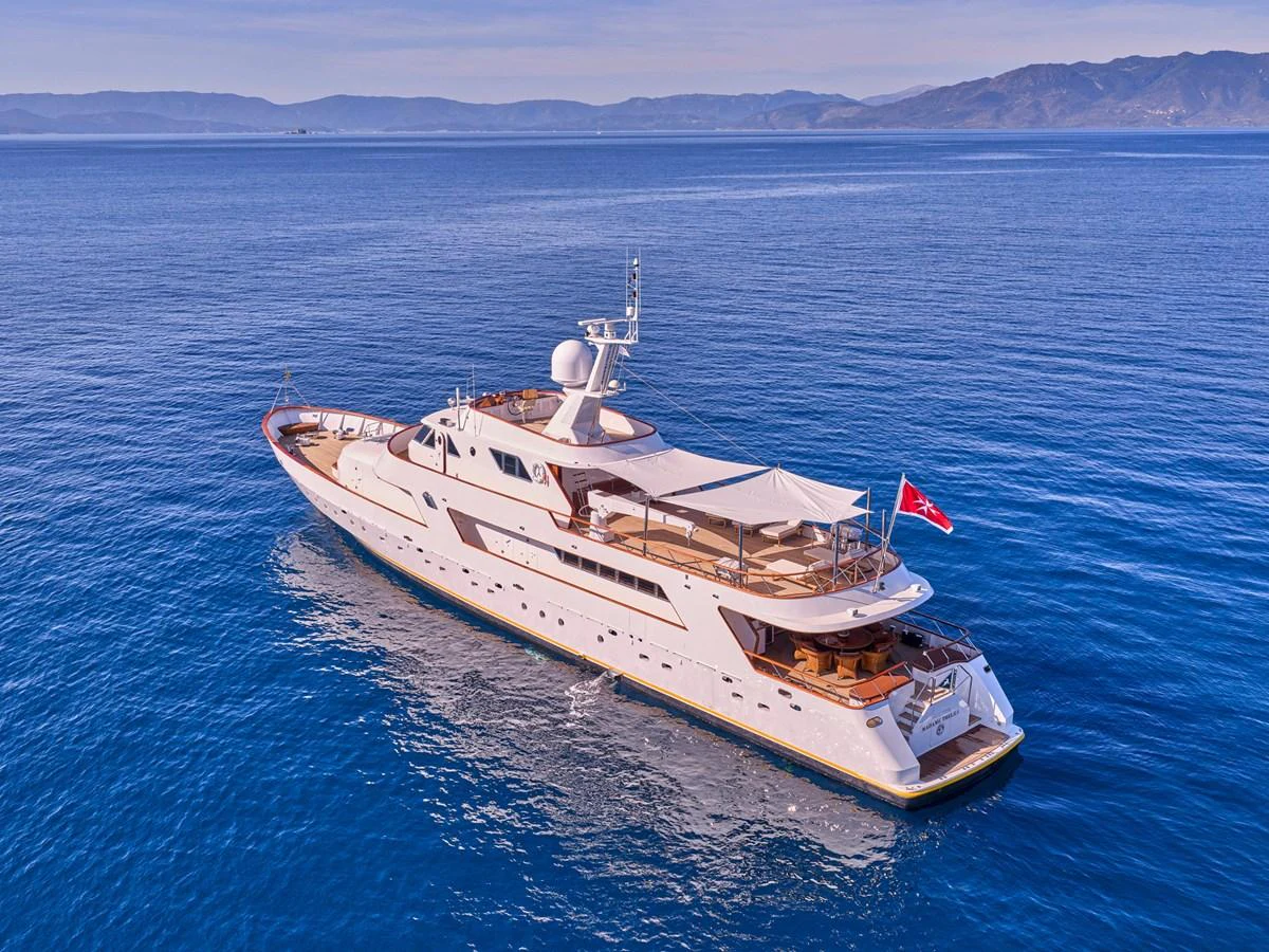 A luxurious yacht cruising on calm blue waters with scenic mountains in the background. aboard RESINA Yacht for Sale