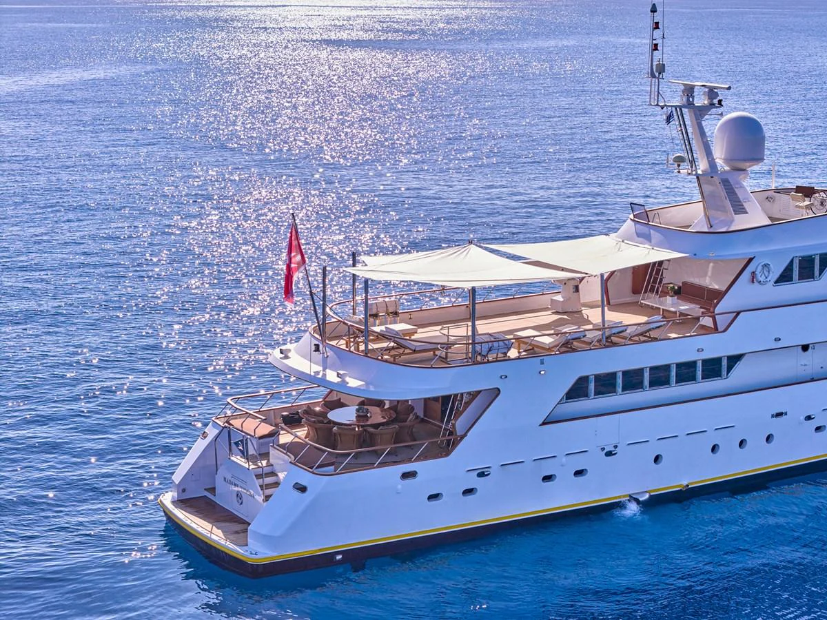 This elegant yacht glides gracefully on the shimmering blue waters, showcasing its luxurious aft deck and sleek design. aboard RESINA Yacht for Sale