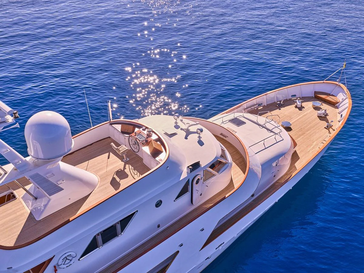 A luxurious yacht glides gracefully on clear blue waters, showcasing its elegant flybridge and sleek design. aboard RESINA Yacht for Sale
