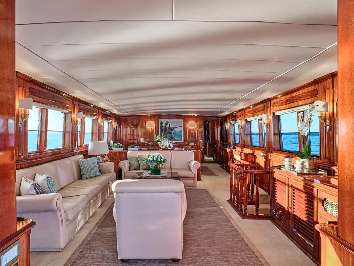 The yacht's salon features luxurious seating and elegant wood finishes, bathed in natural light from large windows. aboard RESINA Yacht for Sale