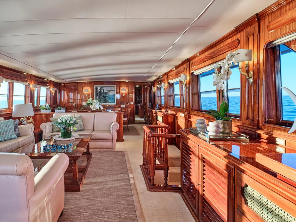 The yacht's salon features elegant wood paneling, plush seating, and large windows offering stunning ocean views. aboard RESINA Yacht for Sale