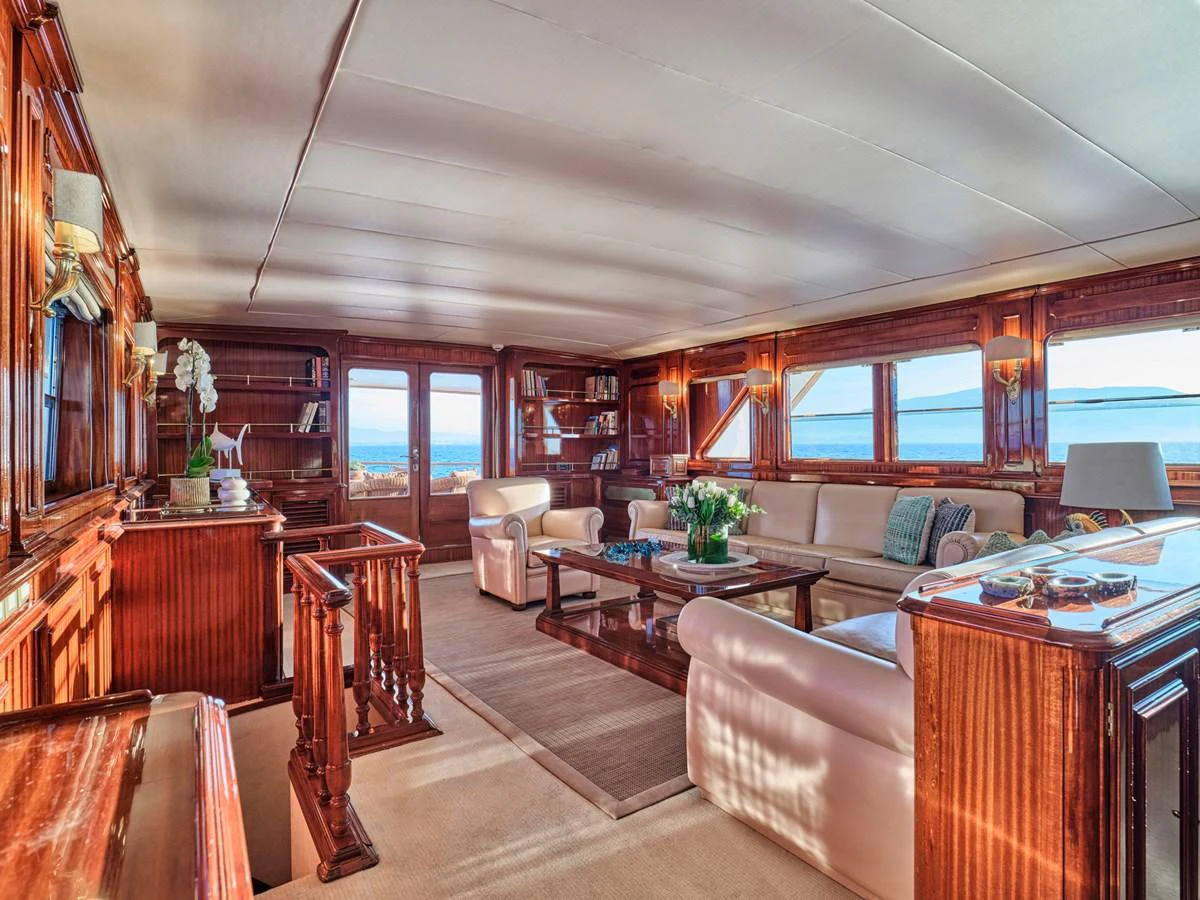 The yacht's salon features luxurious seating, elegant woodwork, and expansive windows offering stunning sea views. aboard RESINA Yacht for Sale