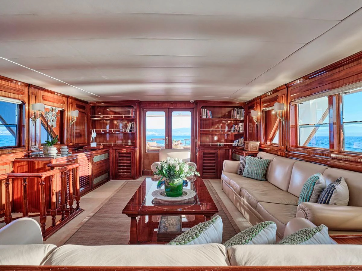 The salon features elegant wood paneling, plush seating, and expansive windows offering stunning ocean views. aboard RESINA Yacht for Sale