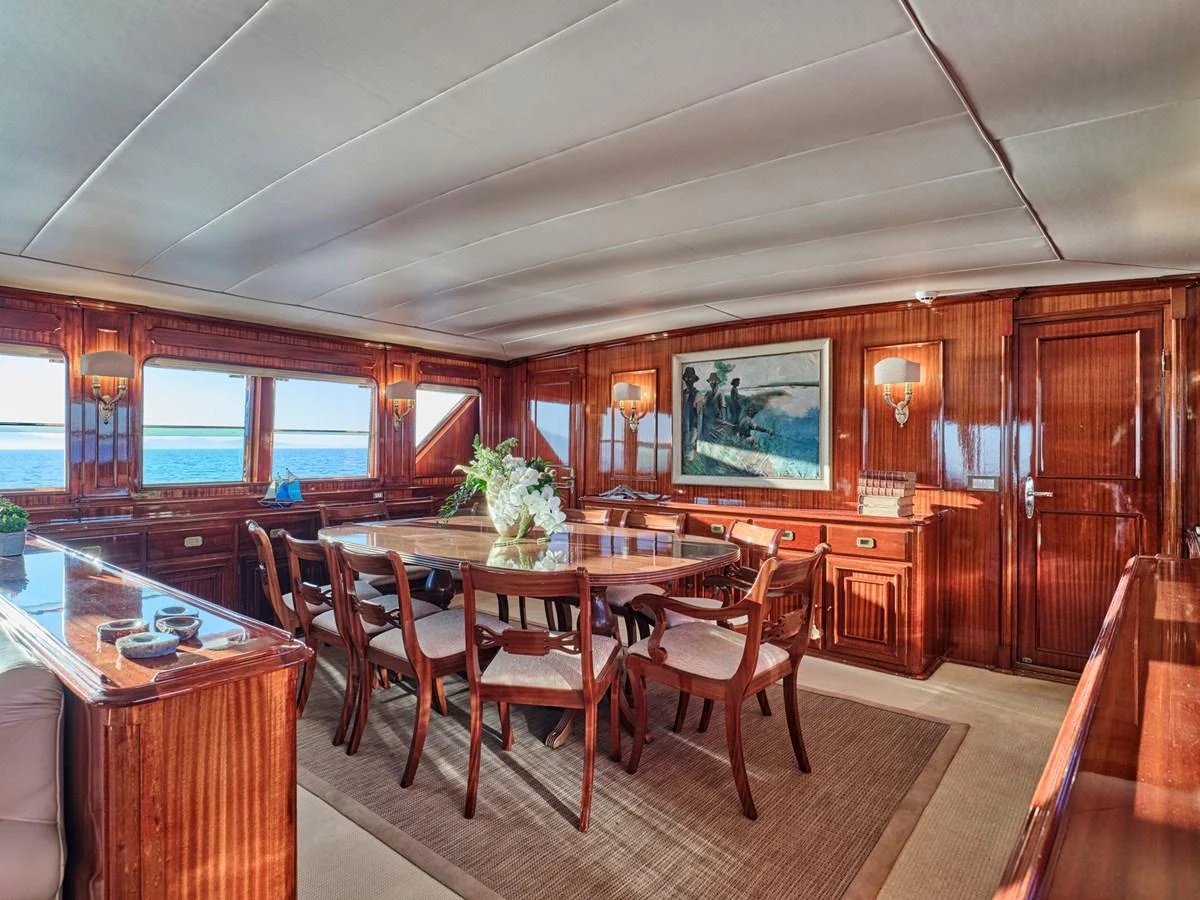 The yacht's dining area features elegant wooden furnishings and large windows offering stunning sea views. aboard RESINA Yacht for Sale