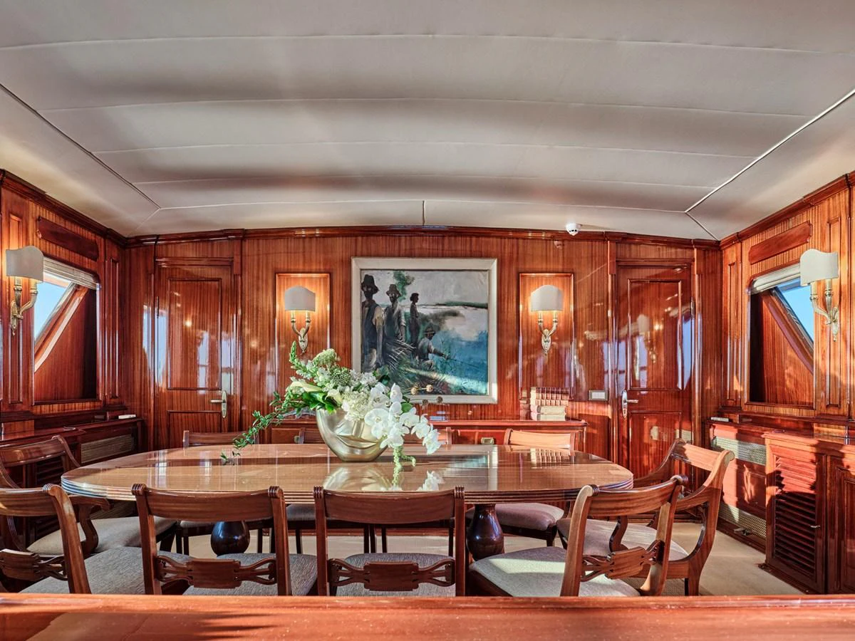 The yacht's dining area features elegant wooden paneling and a large table with comfortable seating. aboard RESINA Yacht for Sale