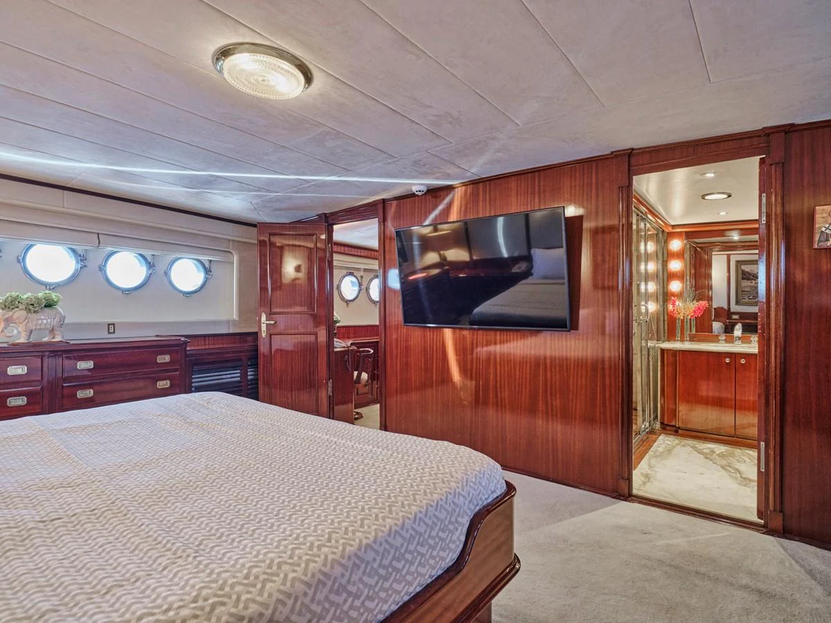 The master stateroom features elegant wood paneling, a large bed, and a flat-screen TV, providing a luxurious and comfortable retreat. aboard RESINA Yacht for Sale