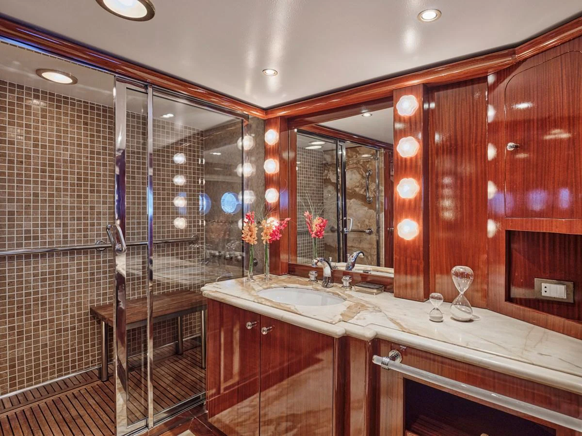 The yacht's bathroom features luxurious wood finishes, a spacious shower, and elegant lighting. aboard RESINA Yacht for Sale