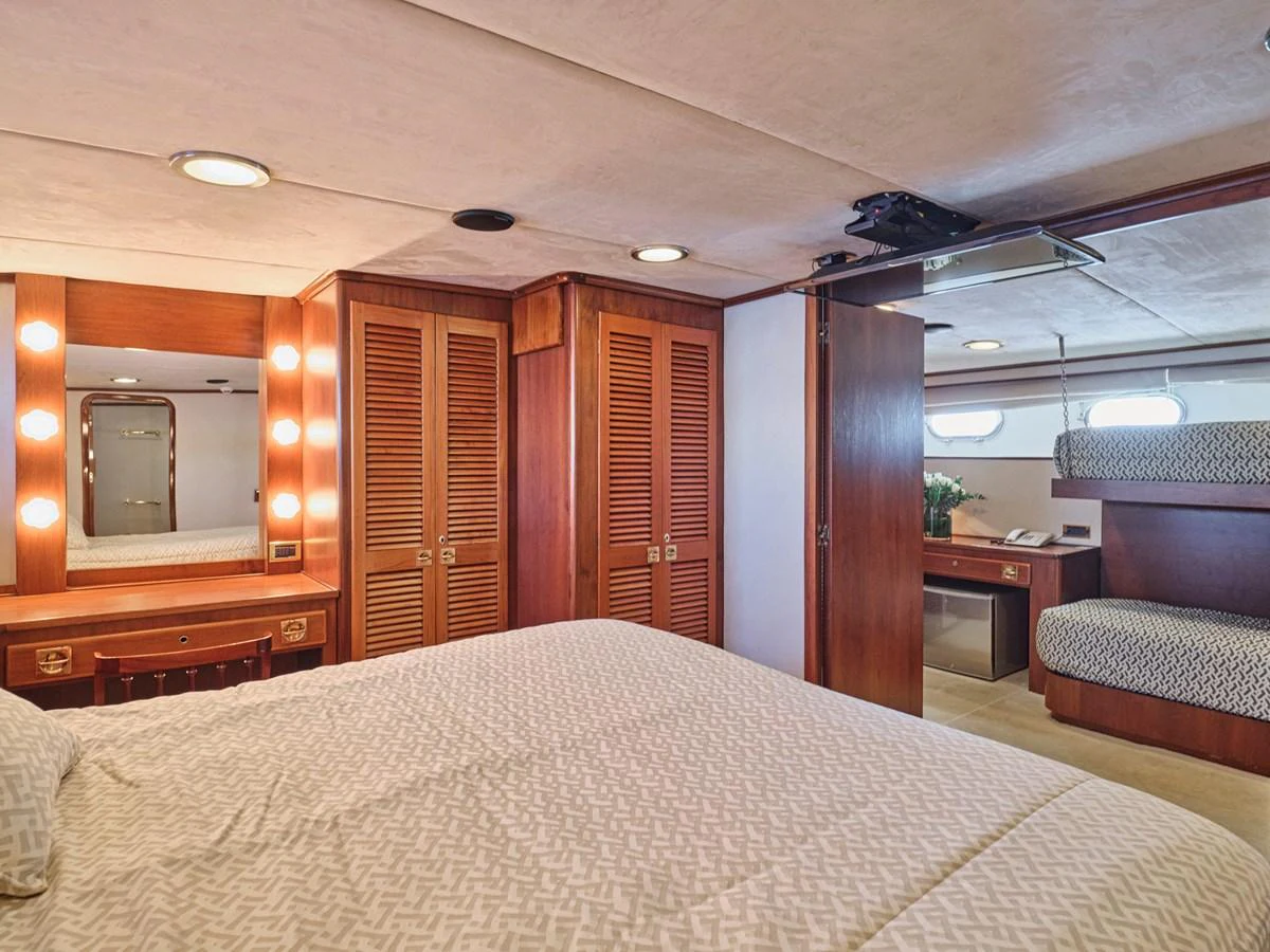 The stateroom features a cozy bed, ample storage, and a vanity area with warm lighting. aboard RESINA Yacht for Sale