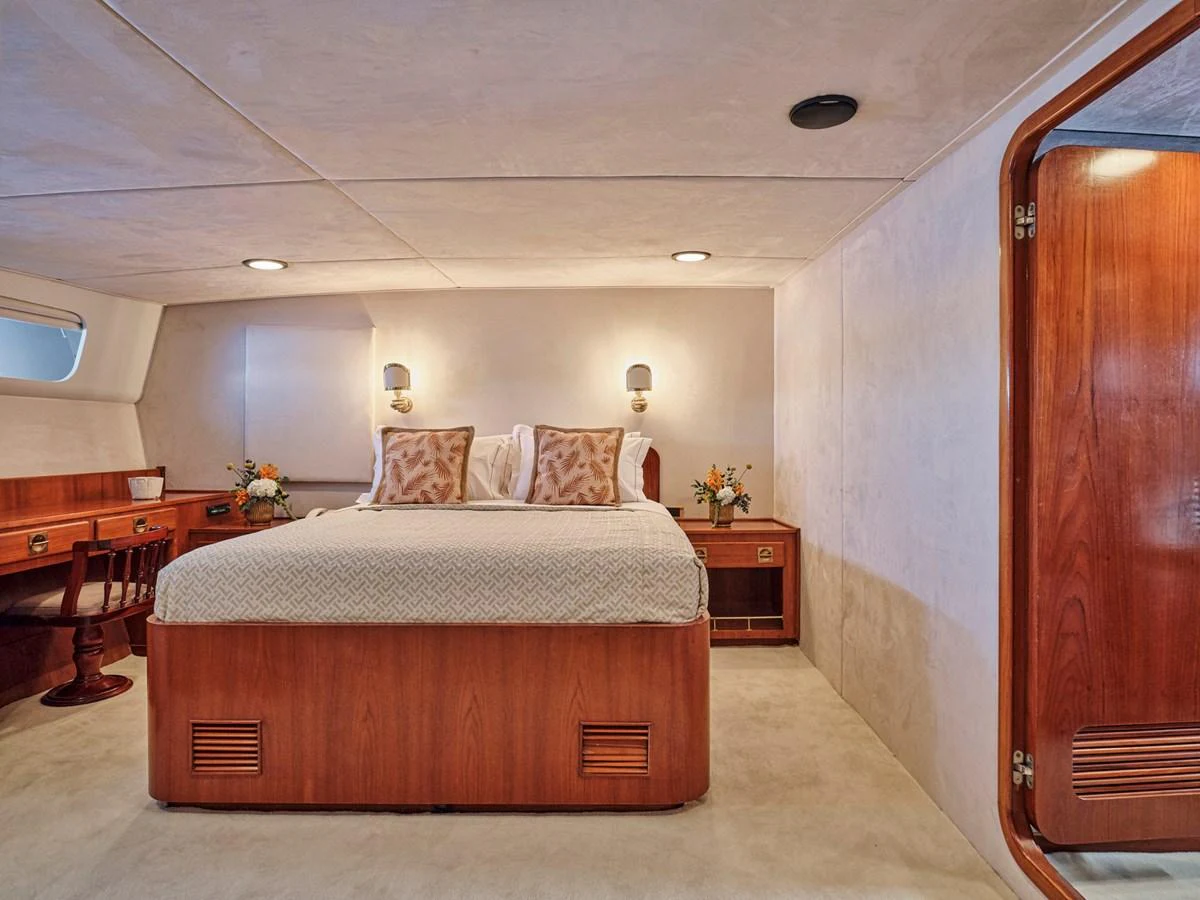 The master stateroom features a spacious bed, elegant wooden furnishings, and soft lighting for a cozy ambiance. aboard RESINA Yacht for Sale