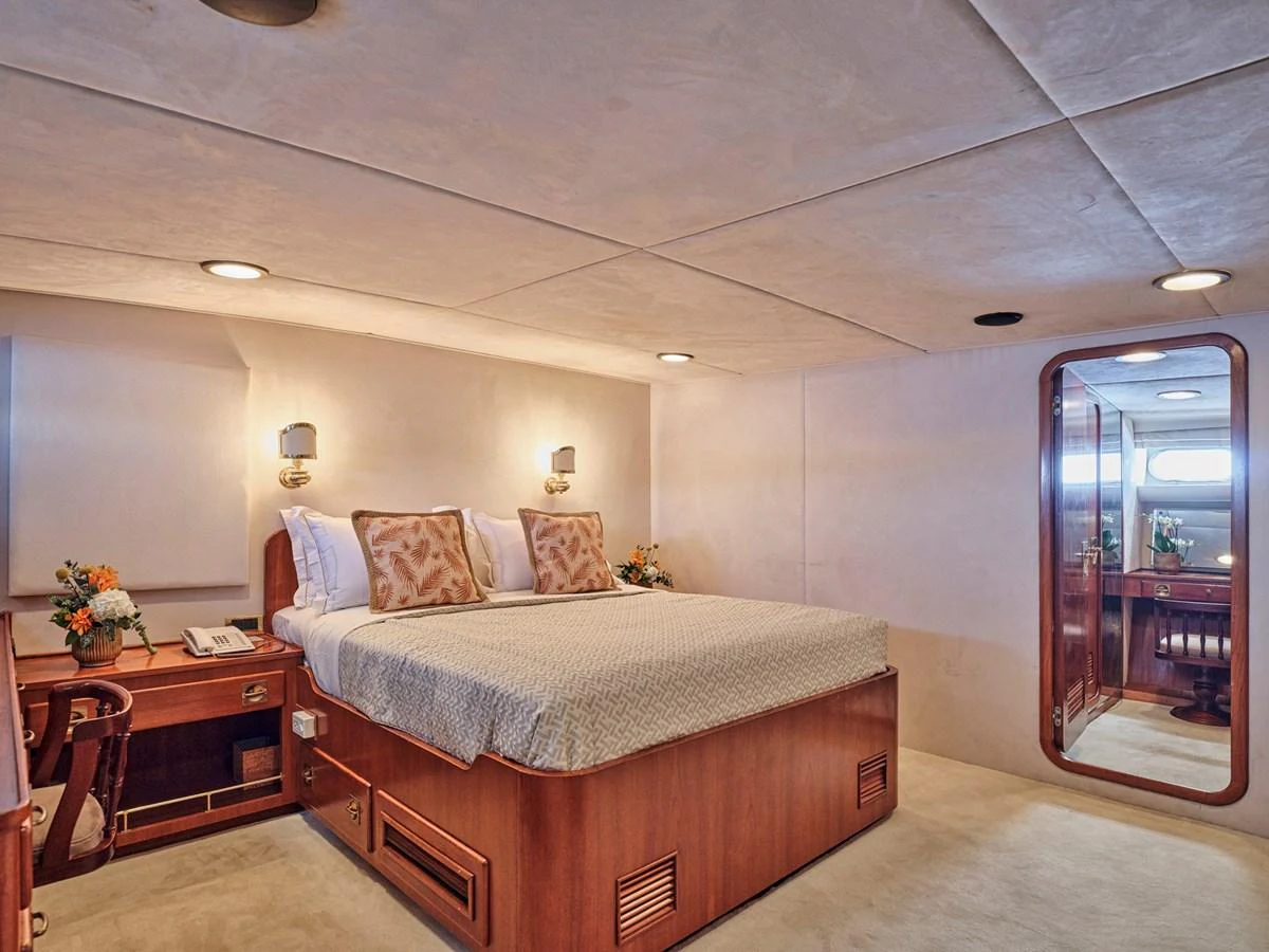 The stateroom features a comfortable bed with elegant bedding and warm lighting, creating a cozy and inviting atmosphere. aboard RESINA Yacht for Sale