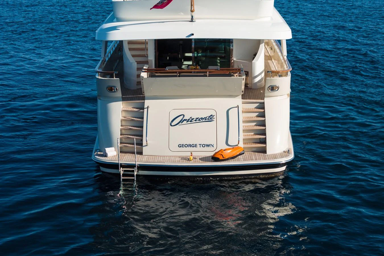 The yacht's stern features a swim platform and steps leading up to the main deck, with the vessel's name prominently displayed. aboard ORIZZONTE Yacht for Sale