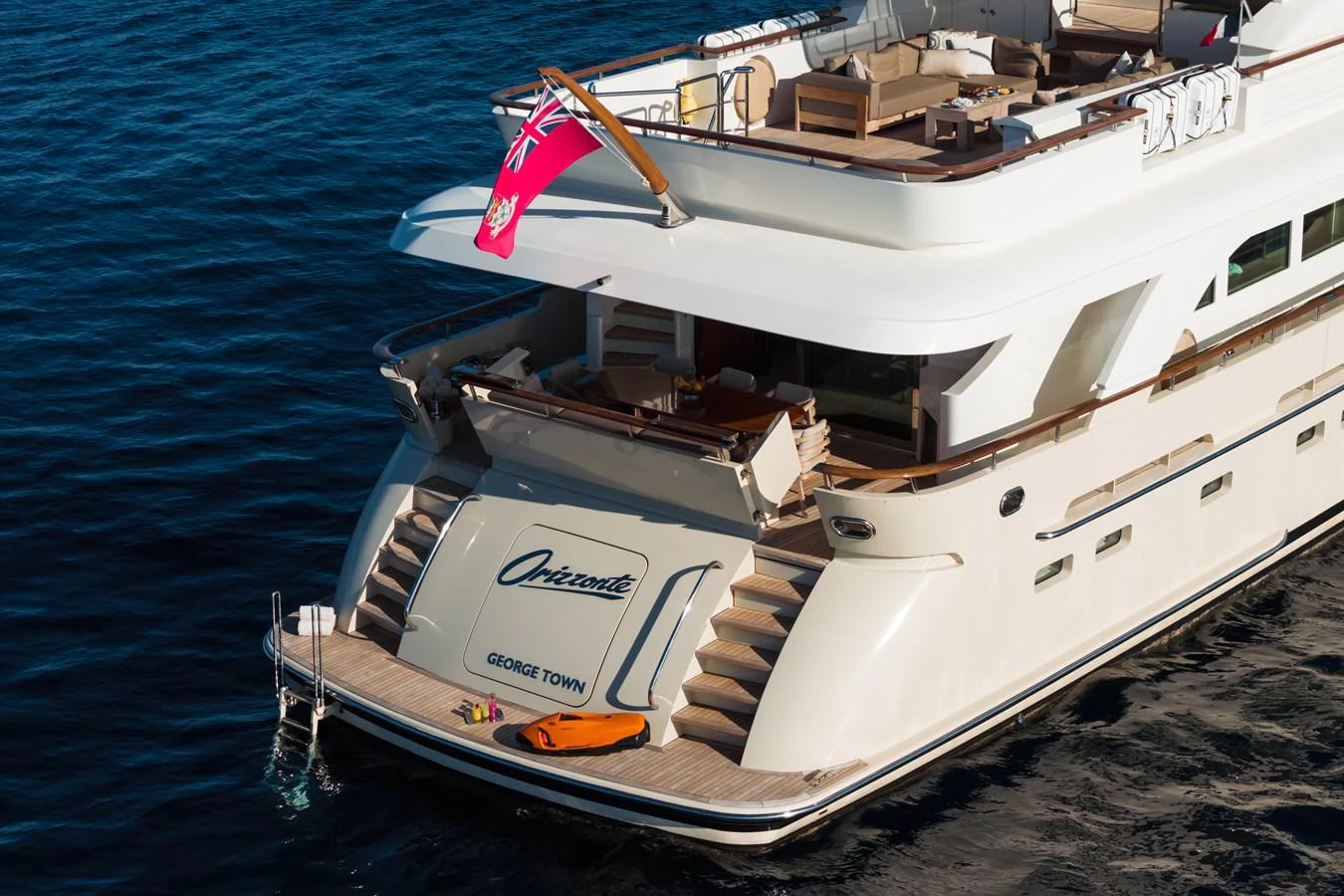 The yacht's aft deck features a spacious lounging area with easy access to the water. aboard ORIZZONTE Yacht for Sale
