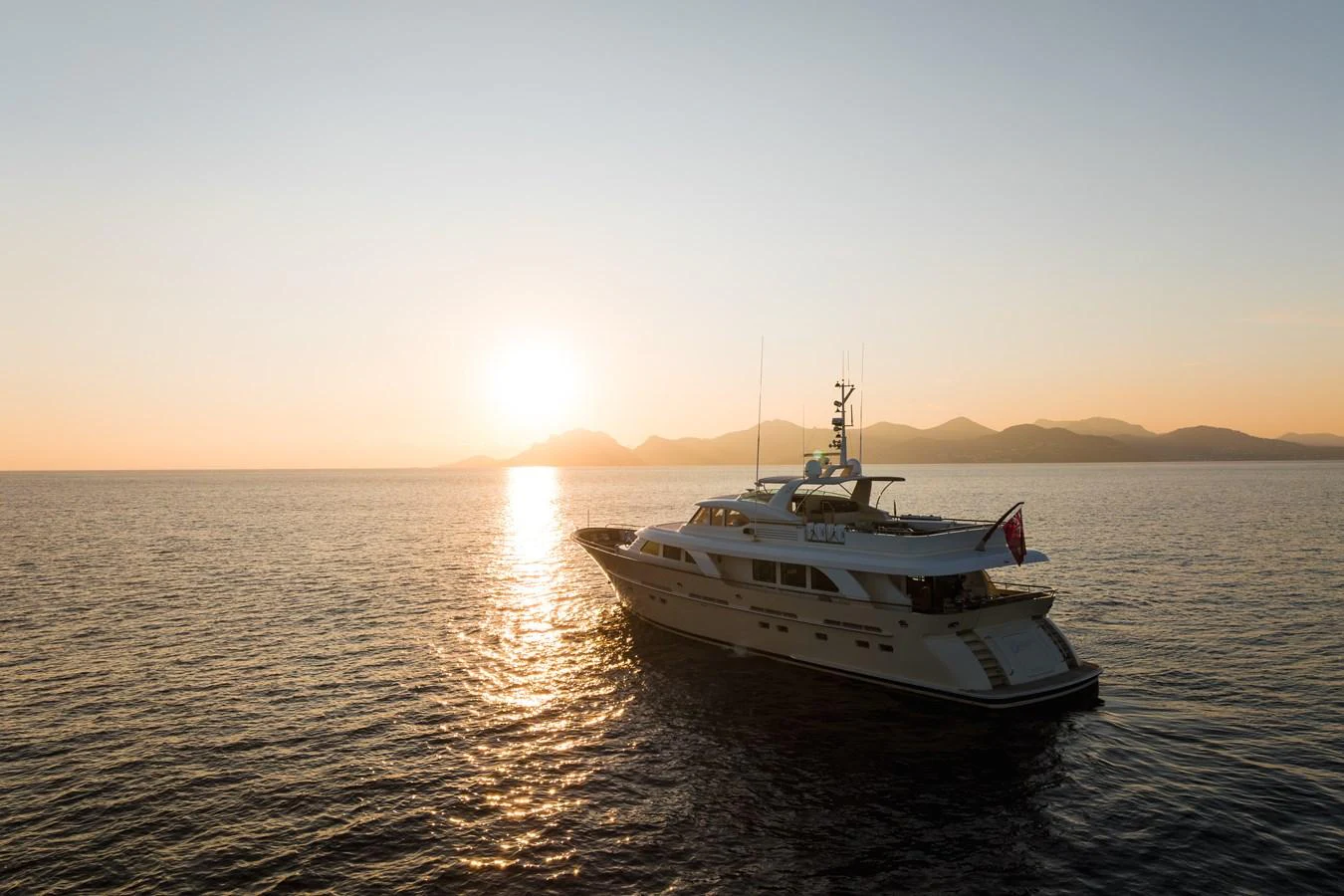 A luxurious yacht sails gracefully at sunset, showcasing its elegant design against a serene backdrop. aboard ORIZZONTE Yacht for Sale