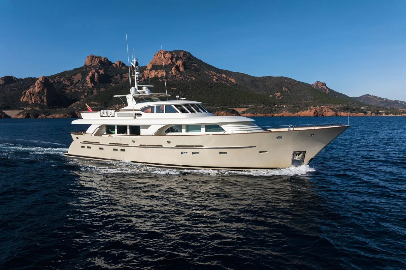 A luxurious yacht cruises through pristine waters with a stunning mountainous backdrop. aboard ORIZZONTE Yacht for Sale
