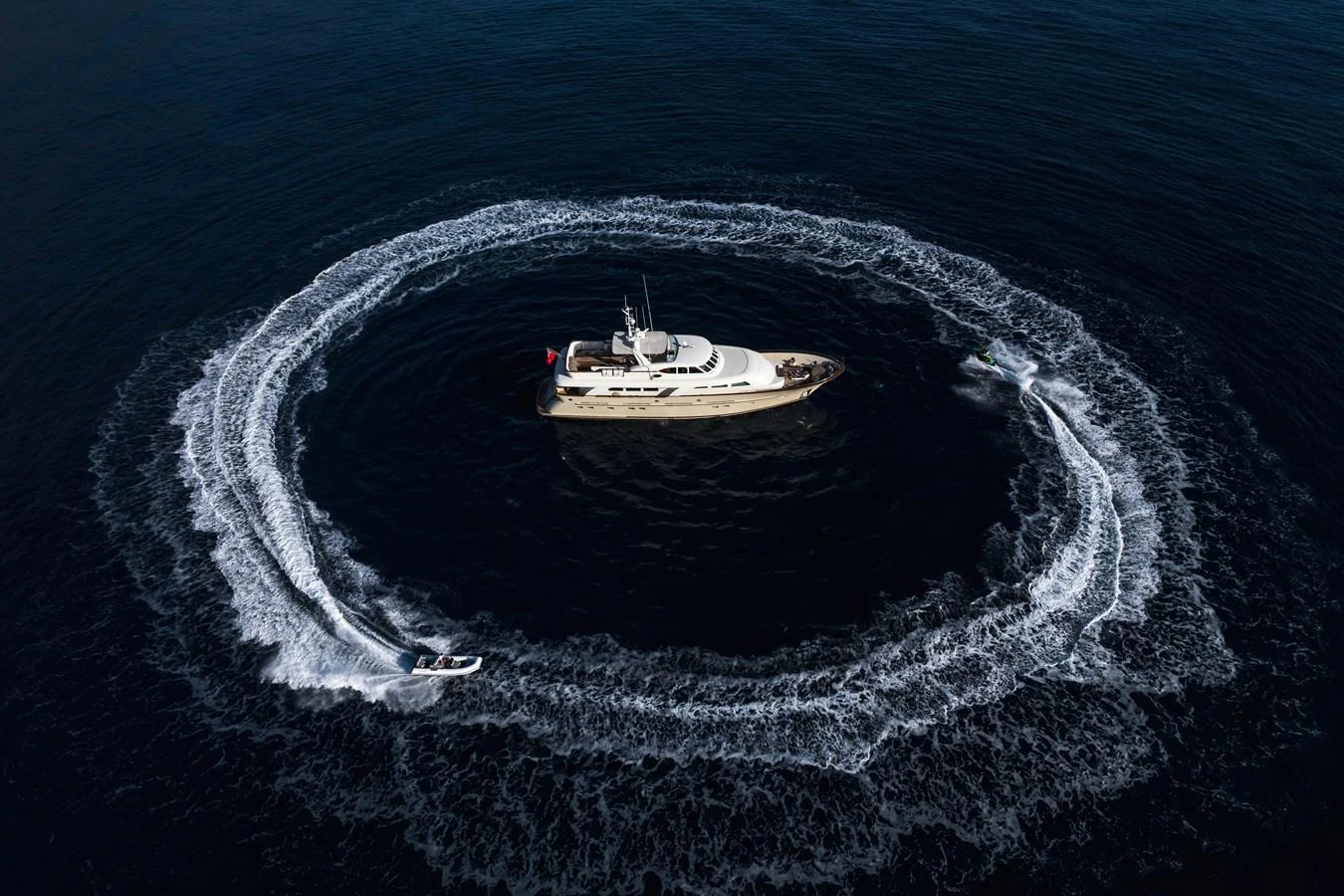 A stunning yacht is encircled by a jet ski creating a dynamic water pattern. aboard ORIZZONTE Yacht for Sale