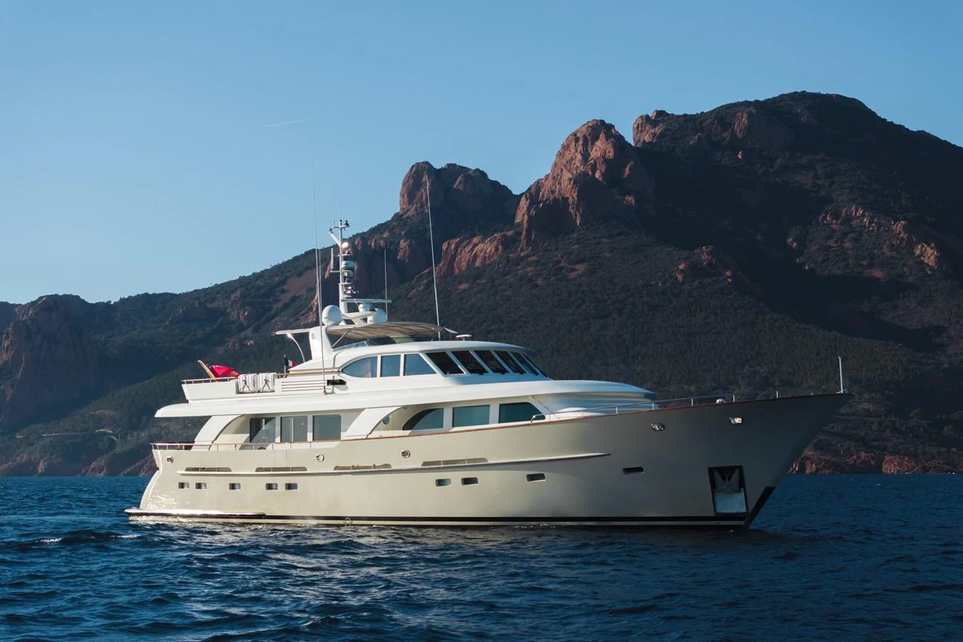 A luxurious yacht glides gracefully on serene waters with a stunning mountainous backdrop. aboard ORIZZONTE Yacht for Sale