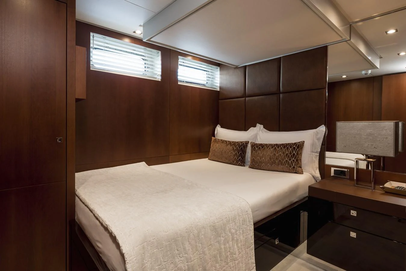 This cozy stateroom features a comfortable bed with elegant bedding and warm wood paneling. aboard ORIZZONTE Yacht for Sale