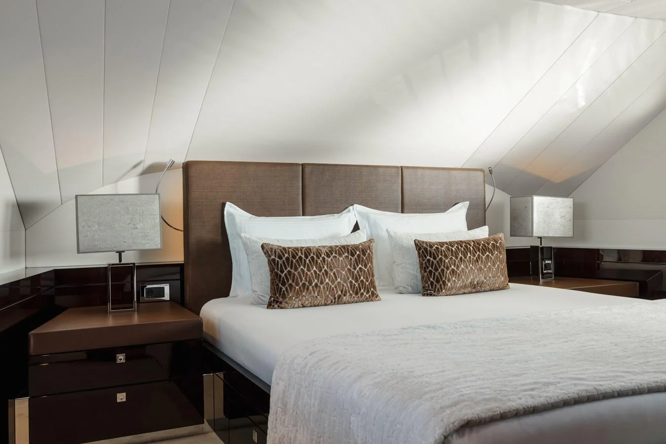 The stateroom features a luxurious bed with elegant bedding and modern bedside lamps. aboard ORIZZONTE Yacht for Sale