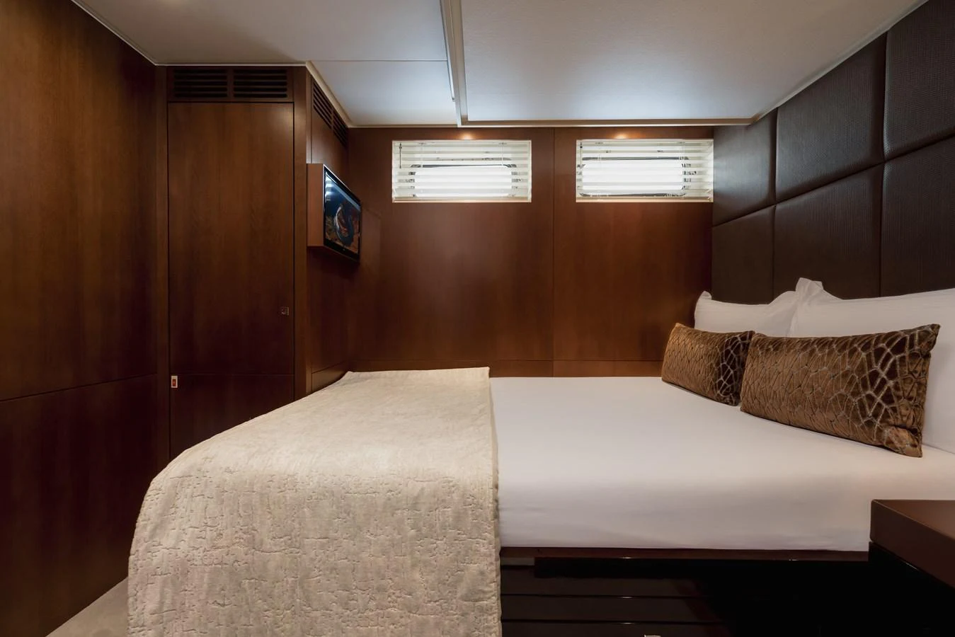 A cozy stateroom featuring a plush bed with elegant bedding and warm wooden accents. aboard ORIZZONTE Yacht for Sale