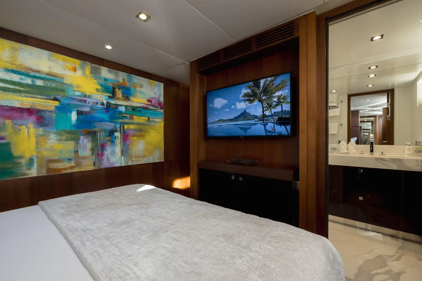 A luxurious stateroom featuring a large bed, modern art, and a flat-screen TV. aboard ORIZZONTE Yacht for Sale