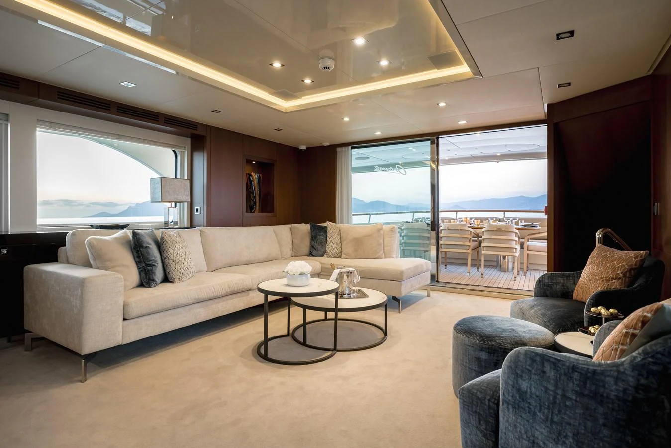 The salon features a spacious seating area with plush sofas and a view of the aft deck through large sliding glass doors. aboard ORIZZONTE Yacht for Sale