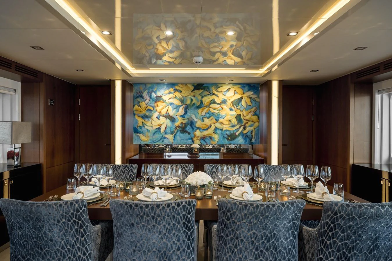 The yacht's dining area features an elegant table setting with plush seating and artistic wall decor. aboard ORIZZONTE Yacht for Sale