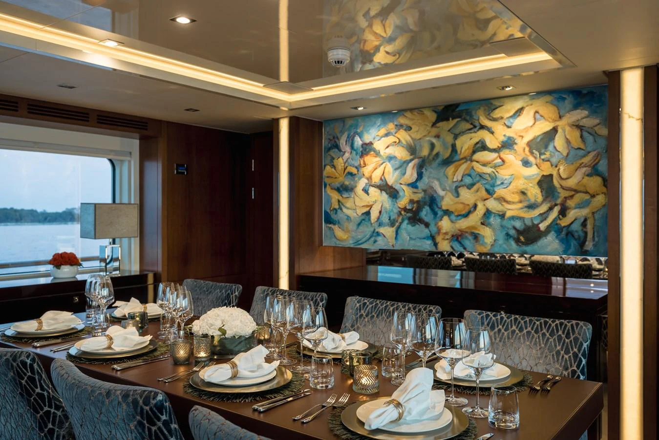 The yacht's dining area features an elegant table setting with a beautiful painting on the wall. aboard ORIZZONTE Yacht for Sale