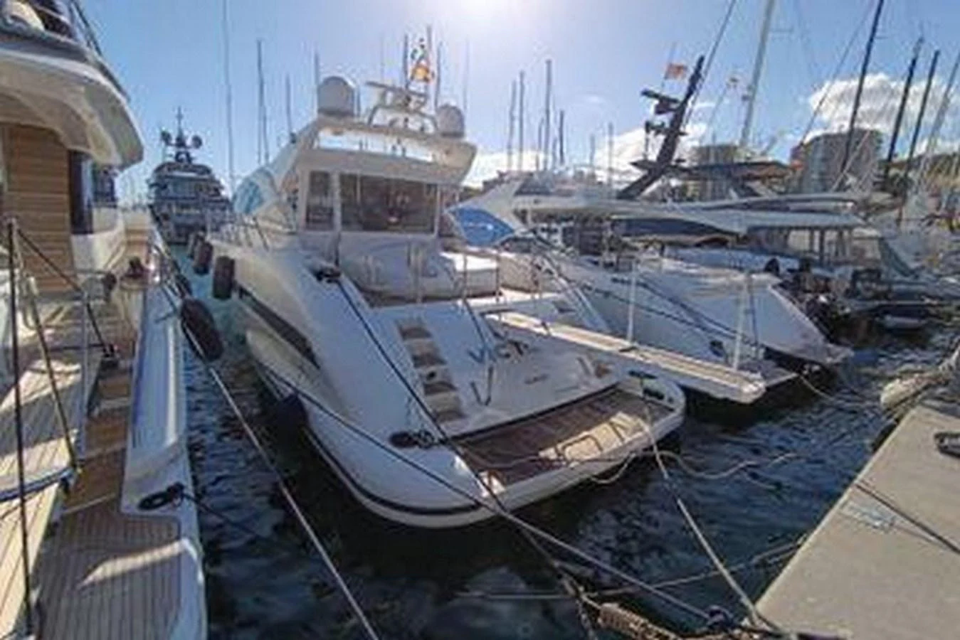 The yacht is docked at a marina, surrounded by other vessels under a clear sky. aboard MANGUSTA 72 Yacht for Sale
