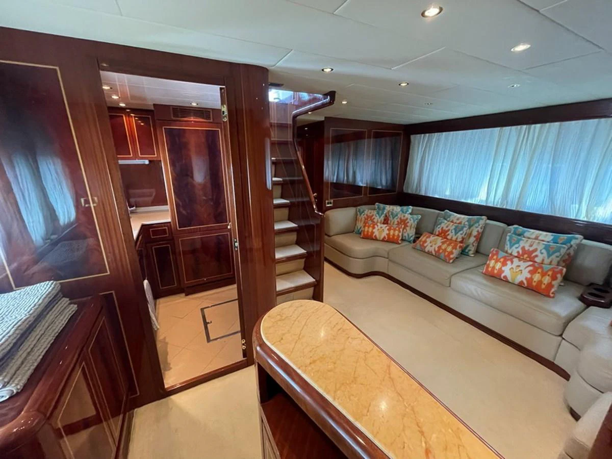 The salon features a comfortable seating area with colorful cushions and elegant wood finishes. aboard MANGUSTA 72 Yacht for Sale