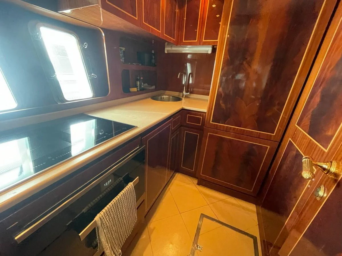 The galley features rich wood cabinetry, modern appliances, and ample counter space. aboard MANGUSTA 72 Yacht for Sale