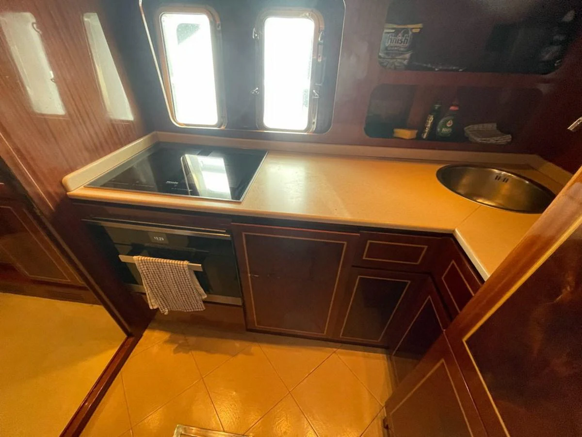 The galley features a sleek countertop with a built-in stovetop and sink, illuminated by natural light from the windows. aboard MANGUSTA 72 Yacht for Sale