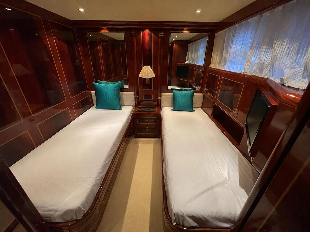 The guest stateroom features twin beds with elegant wood paneling and soft lighting. aboard MANGUSTA 72 Yacht for Sale