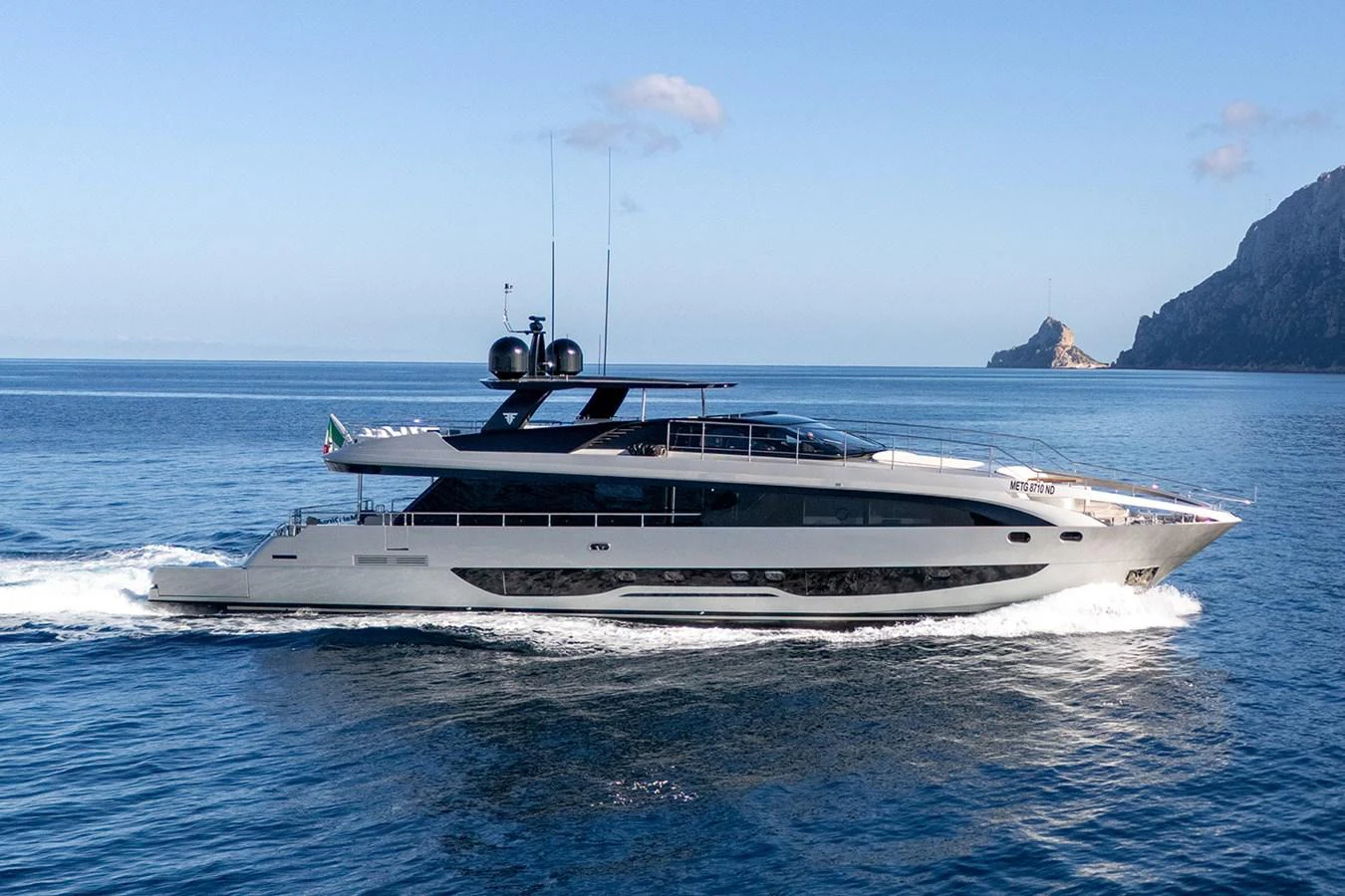 A sleek and modern yacht cruising on calm waters with a scenic coastal backdrop. aboard MAI DIRE MAI Yacht for Sale