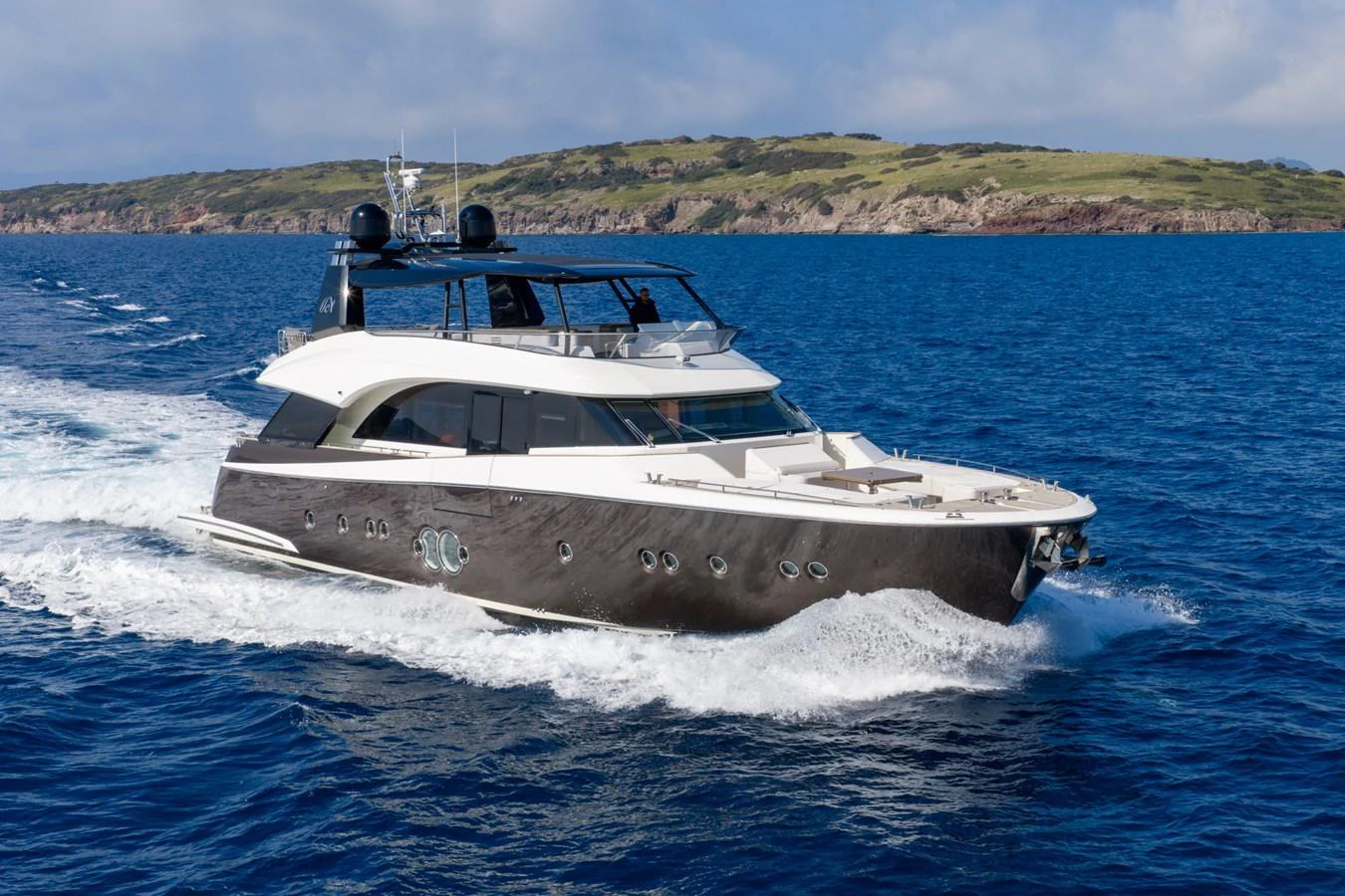 A sleek yacht cruises through the open sea with a scenic coastline in the background. aboard BELLA LUNA Yacht for Sale